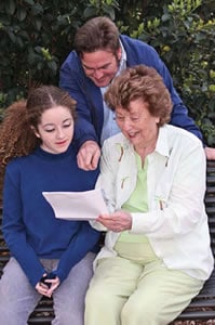 3 People huddled together reading a sheet of papere